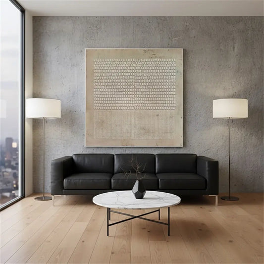 Modern living room with black leather sofa, marble coffee table, and abstract art on gray wall.